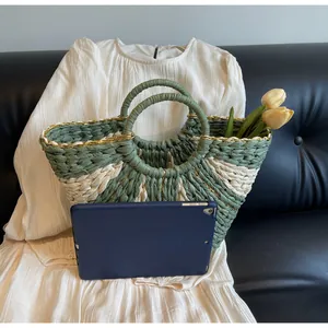 Detail of hand-woven straw tote with green contrast panel and round handles