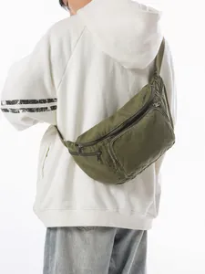 Army green canvas chest bag with multiple zippers shown from a side view on a model