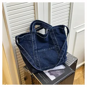 Close-up of dark blue denim tote bag with contrast stitching on a silver suitcase