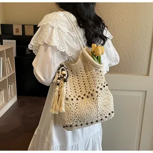 Detail der Häkel-Tote-Bag mit geometrischen Ausschnitten und einer Quaste mit dunklen Perlen