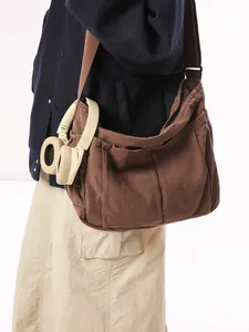 Brown canvas messenger bag with wide shoulder strap and multiple external pockets for women