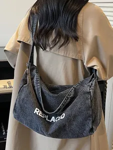 Large dark grey washed denim crossbody bag with white REPLACED letters for casual style