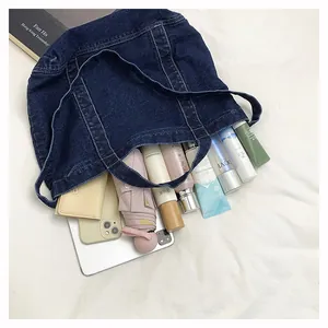 Detail of blue denim tote bag filled with daily items like umbrella and cosmetics