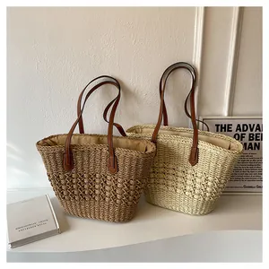 Detailed view of woven straw tote bags showing thick texture and brown leather handles