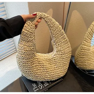 Detail of hand-woven straw beach bag with crescent shape and smooth metal zipper closure