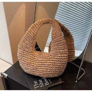 Detailed view of handmade woven straw hobo bag with integrated round handle on a table