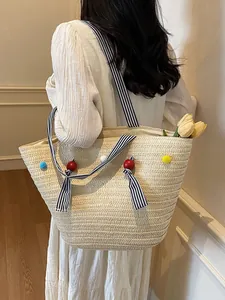 Straw tote bag with striped ribbon bows and colorful pom-poms for beach vacation