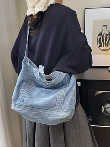 Large light blue denim tote bag with white stitching detail shown on female model