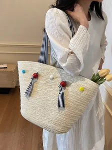 Large hand-woven straw tote bag with colorful pom-poms and black striped ribbon