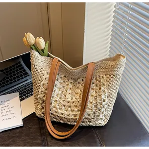 Détail de la texture tressée à jour et des anses en cuir brun d'un sac cabas en paille