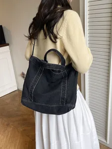 Large black denim tote bag with white contrast stitching and long shoulder strap