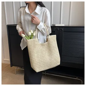 Grand sac cabas en paille tressée crème porté par un mannequin pour l'été