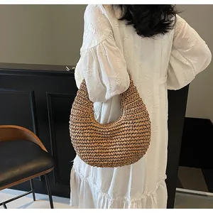 Detail of bohemian hollow straw weave texture on a brown moon-shaped shoulder bag