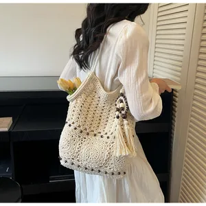 Detail einer cremefarbenen Stricktasche mit Durchbruchmuster und braunen Holzperlen