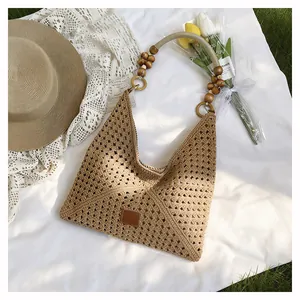 Détail du sac cabas beige tressé main avec poignées en perles de bois et écusson cuir