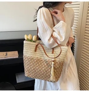 Détail du sac cabas en paille tissée bicolore avec bandoulière en cuir sur modèle
