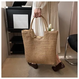 Détail du sac cabas en paille tressée avec finition texturée et doubles poignées rondes