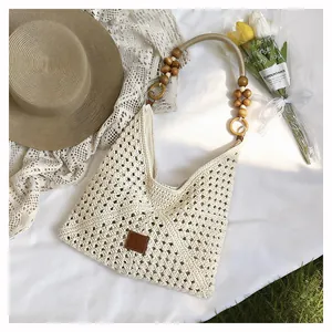 Détail macro du sac cabas beige tissé avec bandoulière originale en perles de bois