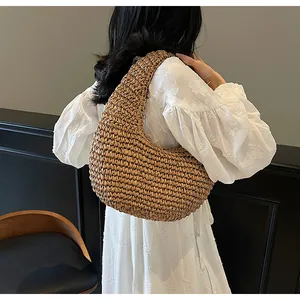 Detail of bohemian hollow straw shoulder bag paired with a white floral embroidered dress