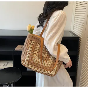 Détail du sac cabas en paille tissé à la main avec motifs géométriques et anses brunes