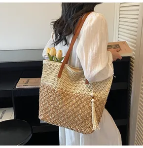 Détail d'un sac cabas tissé main avec bandoulière en cuir et gland sur l'épaule