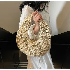 Close-up of a bohemian beige woven straw handbag with a stylish half-moon hobo design