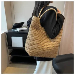 Vue détaillée d'un grand sac cabas en paille porté par un mannequin en intérieur