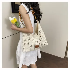 Détail du sac en crochet avec texture tissée, bandoulière en perles et logo en cuir