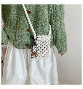 Detail of white cotton crochet crossbody bag featuring a playful cartoon girl pendant