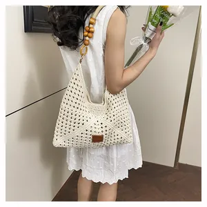 Détail du sac cabas au crochet avec bandoulière en perles de bois et logo en cuir