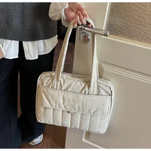Detalle de maletín acolchado beige con costuras verticales y bolsillo con solapa