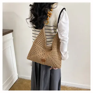 Détail du sac à bandoulière tissé kaki avec bandoulière en perles de bois et écusson cuir