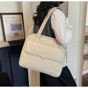 Detalle de bolso acolchado beige para portátil con bolsillo frontal y correa acolchada
