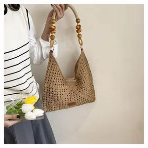Détail d'un sac cabas tissé main avec maille géométrique et anse en perles de bois