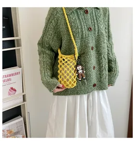 Detail of yellow hollow-out woven phone bag with a cute doll charm and inner pouch