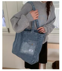Dettaglio della borsa tote in denim a righe verticali con tasca frontale e bottone metallico