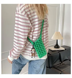 Detail of green handmade woven cotton phone bag with red cartoon charm and crossbody strap