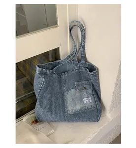 Dettaglio della borsa tote in tela a righe blu con tasca a patta e bottone metallico