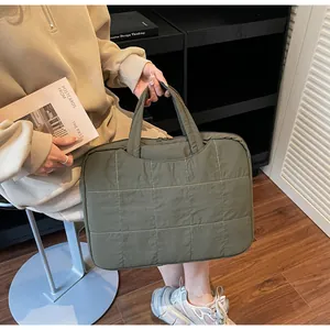 Detail of army green quilted tote bag with white stitching and padded handles