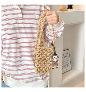 Detail of beige hand-woven hollow crochet phone bag with a cute cartoon doll pendant