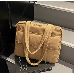 Detalle del bolso tote acolchado caqui con bolsillo frontal y correas acolchadas