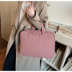Détail d'une sacoche rose pour ordinateur avec motif matelassé et poignées robustes