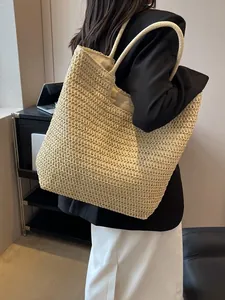Grand sac cabas en paille tressée beige pour les vacances d'été porté par un mannequin