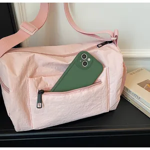 Détail du sac polochon en nylon rose montrant la poche zippée avec un smartphone