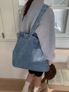 Grande borsa tote in tela denim a righe blu indossata da una modella in un contesto casual