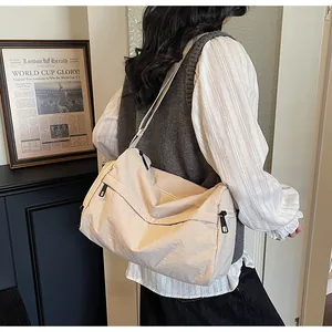 Vue latérale du sac polochon en nylon beige montrant sa grande capacité et son zip noir