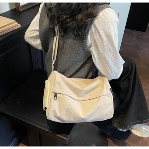 Vue détaillée du sac polochon en nylon beige porté par un mannequin dans un cadre cosy