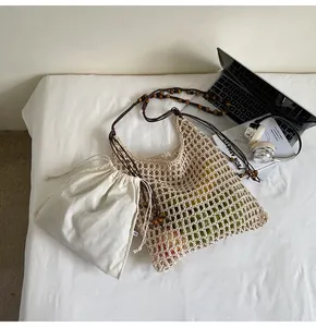 Detail of hollow woven straw tote bag with brown beaded strap and canvas inner pouch