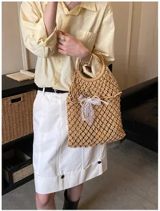 Détail du sac de plage tressé avec poignée en bois, nœud en dentelle blanche et pendentif