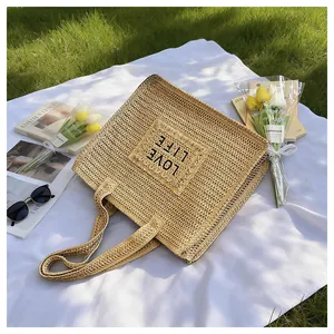 Flat lay of khaki straw tote bag with LOVE LIFE text on a picnic grass background